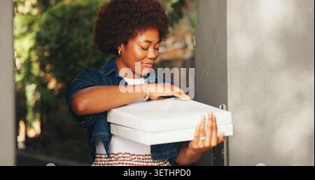 Kiste, Pizzalieferung und schwarze Frau am Eingang zum Haus für Essen oder zum Mitnehmen. Kurier, Mahlzeit und Paket mit zufriedenen Kunden vor der Tür Stockfoto