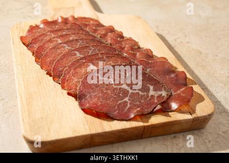 Eine Ansicht von Bresaola-Scheiben auf einem Holzbrett. Stockfoto