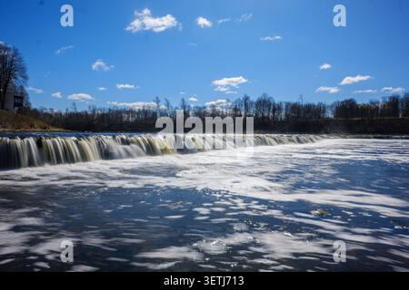 Blick auf Ventas Rumba, den breitesten Wasserfall Europas, mit fließendem Wasser, das über den Kalksteinvorsprung unter einem klaren blauen Himmel in Kuldiga, Kuldiga, fließt Stockfoto