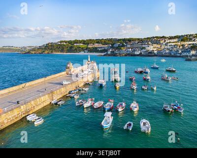 Aus der Vogelperspektive sehen Sie Fischerboote, die im türkisfarbenen Wasser des St. Ives Harbour neben dem Smeaton's Pier und die Küstenstadt in St Ives, England, United, liegen Stockfoto