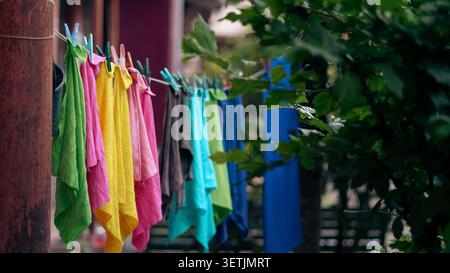 Bunte Handtücher trocknen an einer Wäscheleine in einer sonnigen Gartenumgebung im Freien Stockfoto