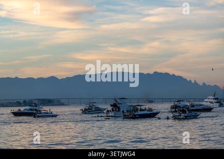 Rio de Janeiro, Rio de Janeiro, Brasilien - 20. Juni 2026: Blick auf die Guanabara-Bucht mit Motorbooten und Menschen bei Sonnenuntergang, mit Bergen und einer Brücke in der Stockfoto