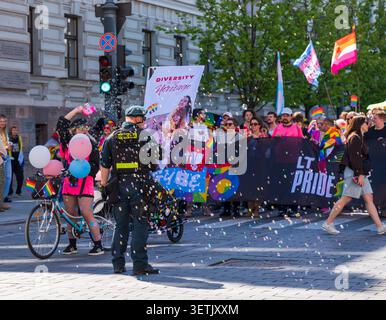 Vilnius, Litauen - 06. Juni 2026: Ansicht von Personen, die an der LT Pride Parade teilnehmen, mit Regenbogenfahnen und Spruchbändern, während ein Polizeibeamter anwesend ist Stockfoto