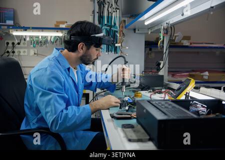 Ein Löttechniker von Mann konzentriert sich voll und ganz auf die Arbeit an einem Computer Stockfoto