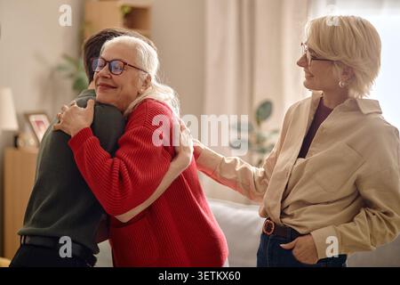 Eine ältere Frau umarmt den erwachsenen Sohn während eines Familienbesuchs zu Hause Stockfoto