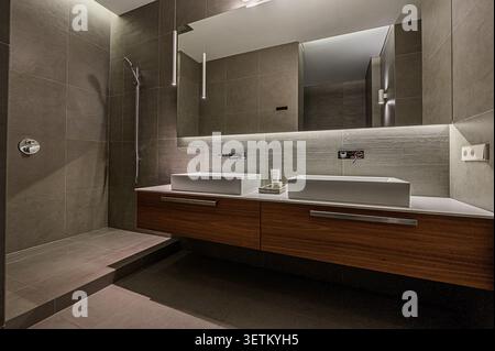 Ein modernes Bad mit zwei Waschbecken, Holzschränken und elegantem, minimalistischem Design Stockfoto
