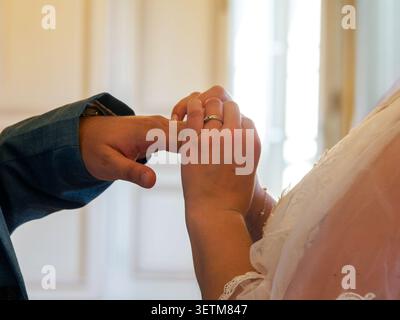 Nahaufnahme einer Braut, die einen Ehering auf den Finger ihres Partners legt, während der Ringwechsel bei einer Hochzeitszeremonie in Frankreich. Stockfoto