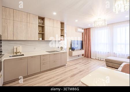 Moderne Küche und Wohnbereich mit warmen Holztönen, eleganten Schränken und heller Beleuchtung schaffen einen gemütlichen und stilvollen Raum Stockfoto
