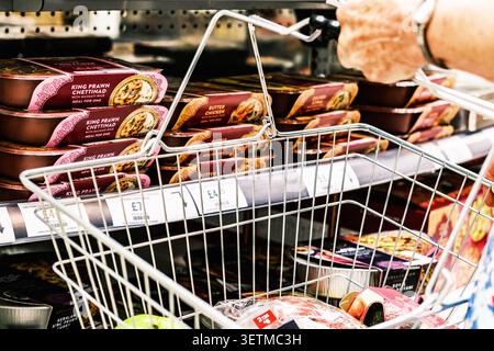 Epsom London UK, 22. Juni 2026, Nahaufnahme einer Mans Hand, die einen Shopping Basket hält und Ready Meals im indischen Stil durchsucht Stockfoto