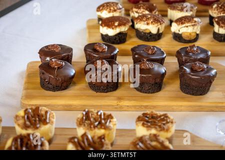 Verschiedene Desserts, einschließlich Schokolade und Tiramisu, serviert auf Holztabletts auf weißer Tischdecke. Stockfoto