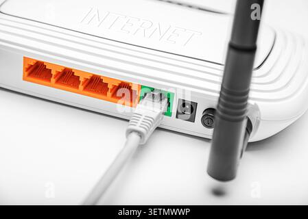 Netzwerkkabel an der Rückseite eines weißen Internet-Routers angeschlossen. Stockfoto