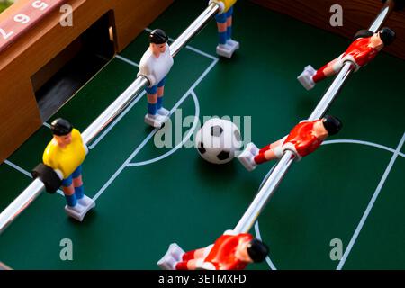 Tischkicker mit roten und weißen sowie gelben und blauen Plastikspielern, die die farbliche Teamidentität im Tischfußball hervorheben. Stockfoto