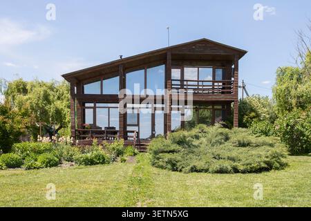 Modernes hölzernes Landhaus mit großen Panoramafenstern und grünem Landschaftsgarten Stockfoto