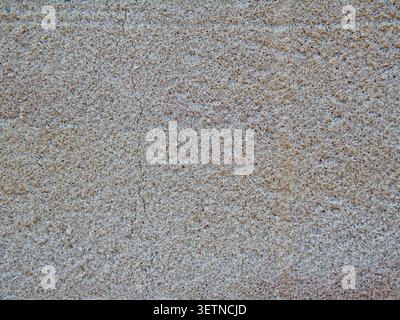 Close-up-Makro einer rauen Putzwandstruktur mit feiner Mineralkörnung und natürlichen Oberflächendetails. Ideal für Hintergründe und Bauthemen. Stockfoto
