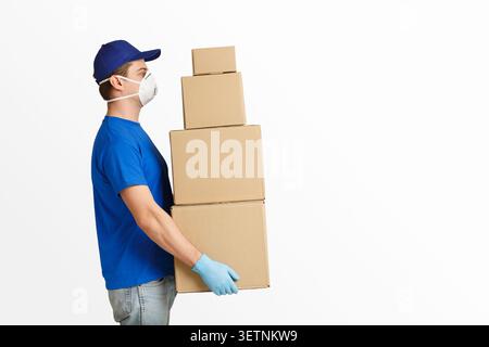 Paketzustellung während des Quarantänekonzepts. Kurier in Schutzmaske hält eine Menge von Kartons Stockfoto