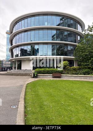Das kreisförmige CIS-Gebäude an der Northumbria University, Newcastle upon Tyne, England, bietet moderne Glasfassadenarchitektur und Rasenflächen. Stockfoto