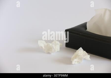 Schwarze Taschentücher mit gezogenen Taschentüchern und zerknitterten weißen Papiertüchern Stockfoto