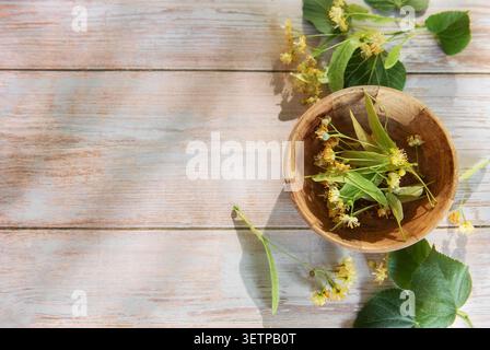 Lindenblüten und -Blätter in einer Holzschale für die Zubereitung von Kräutertee Stockfoto