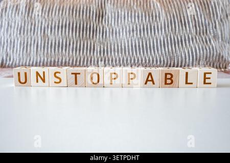 Unaufhaltsames, motivierendes Wort aus Buchstaben auf Holzwürfeln Stockfoto