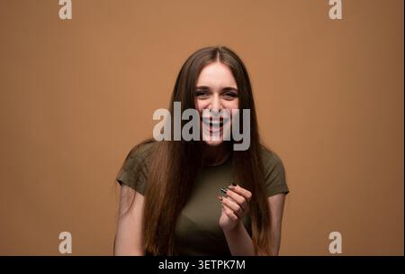 Junge Frau lächelt und lacht mit aufrichtiger Freude, drückt positive Emotionen und Glück aus Stockfoto