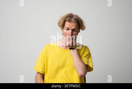 Junger Mann, der den Mund mit der Hand bedeckt, Schock und vollständige Überraschung ausdrückt, Unglauben über ein unerwartetes Ereignis oder eine plötzliche Nachricht empfindet Stockfoto