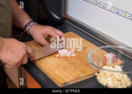 Mann, der rohe Pancetta in kleine Stücke in einer Küche hackt Stockfoto