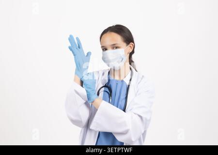 Junge Ärztin mit chirurgischer Maske und Gummihandschuhen auf weißem Hintergrund Stockfoto