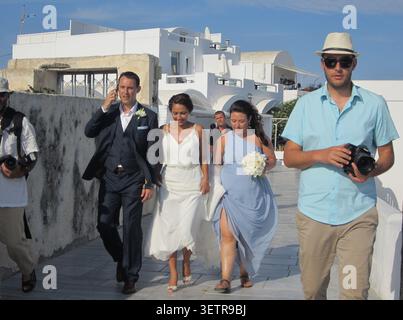 Professionelle Fotografen arbeiten während eines Sommer-Hochzeits-Fotoshootings mit einem frisch verheirateten Paar und einer Brautjungfer auf einer Straße in Oia Santorini, Griechenland. Stockfoto