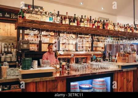 Hannover, Deutschland - 21. April 2026: Barkeeper serviert Drinks hinter einer traditionellen Holzbar in einer historischen Taverne und einem Restaurant in der Georgstraße in Stockfoto