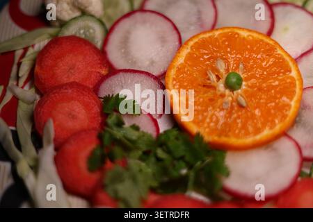 Ein lebendiges Teller mit frischem Salat, kunstvoll arrangiert mit farbenfrohen Gemüsen und Früchten, zeigt gesundes Essen in einem modernen Lebensstil. Stockfoto