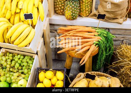Die Verkaufsstände sind mit verschiedenen Obstgemüse wie Bananen, Trauben und Karotten in der lokalen Markierungsszene gefüllt Stockfoto