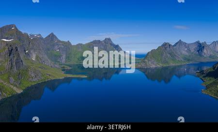 Atemberaubende Aussicht aus der Luft auf den dramatischen Fjord der Lofoten, umgeben von scharfen Granitgipfeln, unberührtem blauem Wasser und üppigen grünen Tälern mit Stockfoto