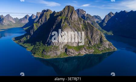 Atemberaubende Aussicht auf einen dramatischen felsigen Berggipfel, umgeben von tiefblauem Wasser auf den Lofoten-Inseln, Norwegen. Robustes alpines Gelände Stockfoto