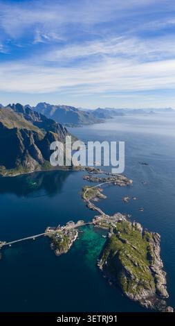 Dramatische Aussicht auf die Lofoten-Inseln in Norwegen, mit steilen felsigen Bergen, türkisfarbenem Wasser, traditionellem Fischerdorf und Stockfoto