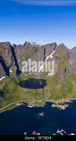 Atemberaubende Aussicht auf die Lofoten-Inseln mit dramatischen zerklüfteten Gipfeln, alpinen See, grünen moosbedeckten Hängen und traditionellem Norwegischen Stockfoto