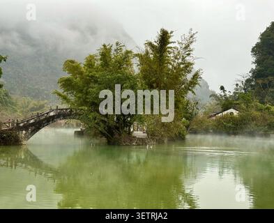 Chinesische Steinbogenbrücke über Misty Lake in Karstlandschaft Stockfoto