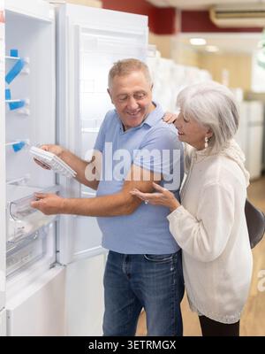 Ein älteres Paar kauft in einem Geschäft ein und wählt einen neuen Kühlschrank im Supermarkt Stockfoto