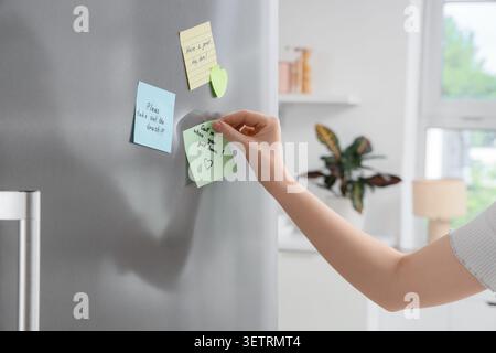 Händige Haftnotizen mit Erinnerungen an eine Kühlschranktür in einer modernen Küche Stockfoto