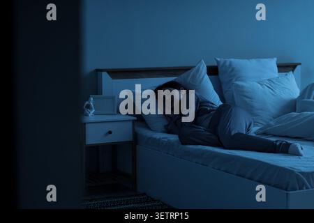 Frau, die nachts im Bett in einem dunklen Schlafzimmer schläft Stockfoto