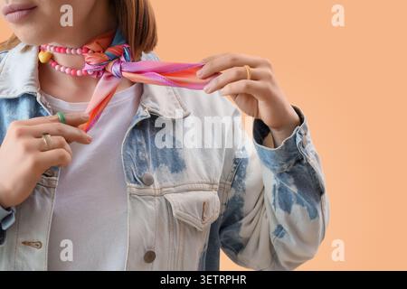 Frau, die einen farbenfrohen Schal um den Hals bindet, trägt eine Jeansjacke Stockfoto