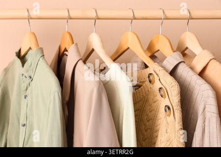 Neutrale Kleidung hängt an Holzbügeln im Kleiderschrank Stockfoto
