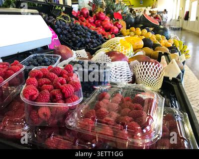 Nahaufnahme eines farbenfrohen Obststands auf einem lokalen Markt, der mit frischen Himbeeren, Heidelbeeren, Trauben, Mangos, Bananen, Papayas, Kiwis, Melone Stockfoto