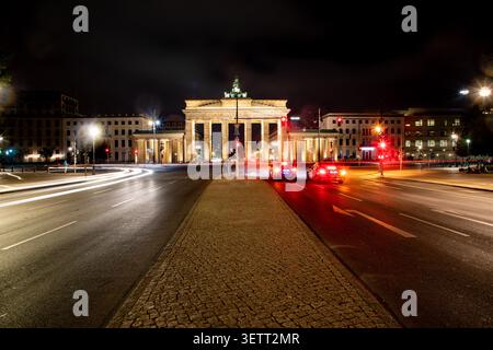 Blick auf das beleuchtete Brandenburger Tor bei Nacht mit Lichtspuren von vorbeifahrenden Autos auf der Straße in Berlin, Berlin, Deutschland. Stockfoto
