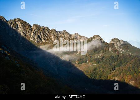 Blick auf den Botev Peak in den Balkanbergen mit felsigen Hängen, Herbstlaub und niedrigen Wolken unter einem klaren blauen Himmel in den Balkanbergen, Stockfoto