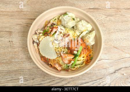Chinesische Eigelnudeln mit rotem Barbecue-Schweinefleisch und Knödeln mit Krabbenfleisch in klarer Suppe auf einer Schüssel Stockfoto