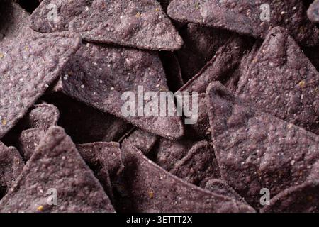 Eine Ansicht von oben nach unten auf einen Haufen blauer Maistortilla-Chips als Hintergrund. Stockfoto