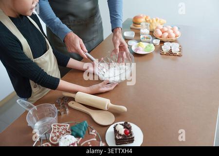 Zugeschnittener Schuss von Vater und Tochter, die Zutaten in einer Glasschale zum Backen rühren Stockfoto