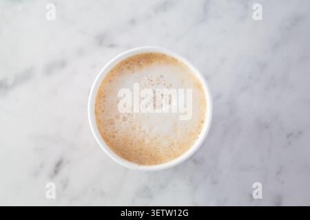 Ein Blick von oben nach unten auf einen Cappuccino in einem Pappbecher. Stockfoto