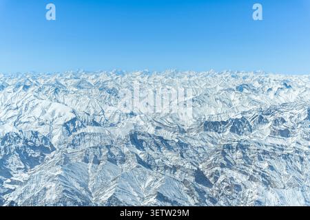 Ein atemberaubendes Luftbild in großer Höhe, das die riesigen und majestätischen, schneebedeckten Gipfel, Grate und tiefen Täler des Himalaya unter einem c einfängt Stockfoto