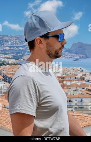 Ein Mann steht vor dem Hintergrund der Dächer der Altstadt, die sich an der Küste des Mittelmeers befindet. Berge und Himmel im Hintergrund. Altea. Stockfoto